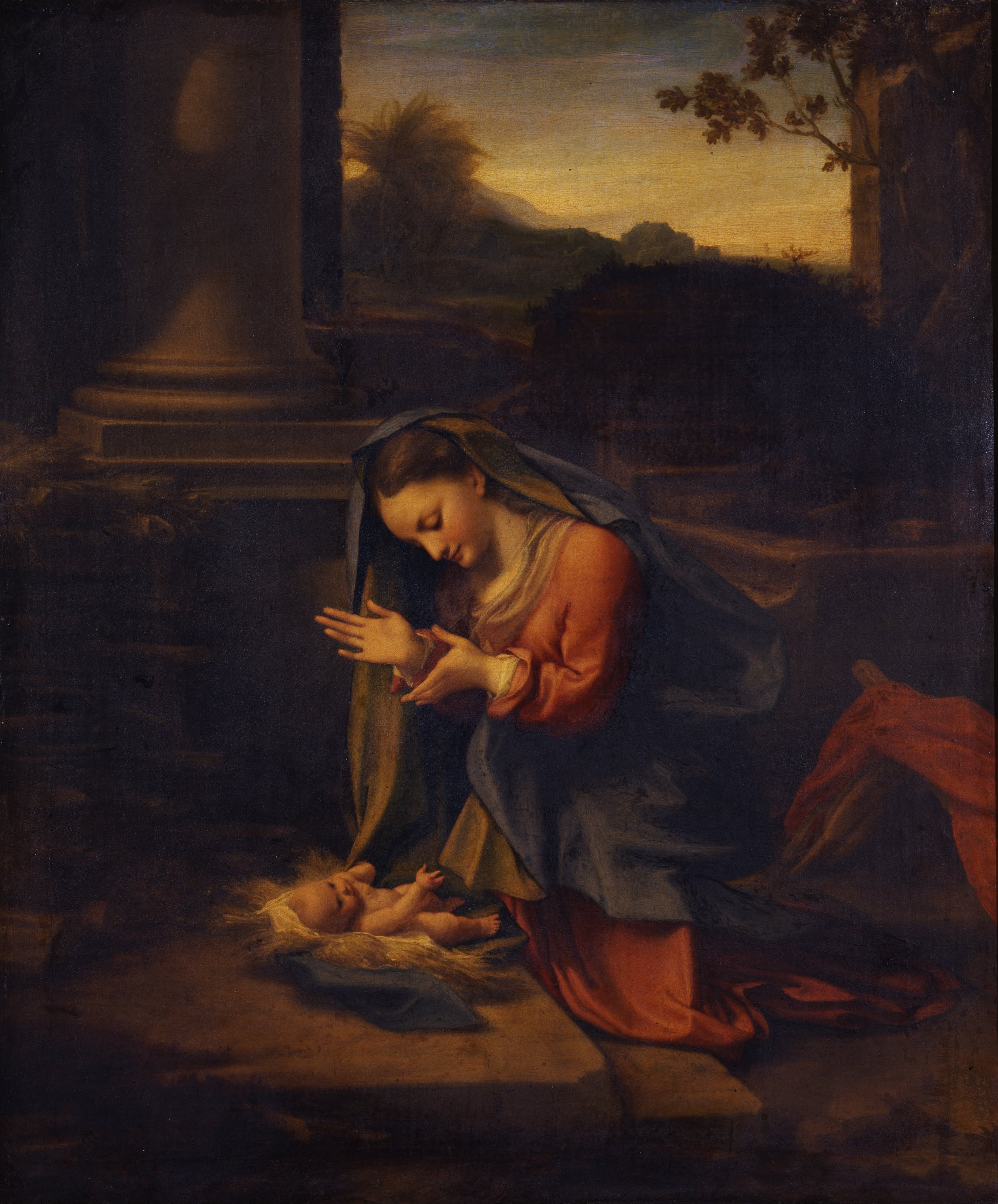 Correggio’s Adoration of the Christ Child: the Virgin kneels with open hands before the baby lying on straw and a fold of blue cloth, beside a ruined column.