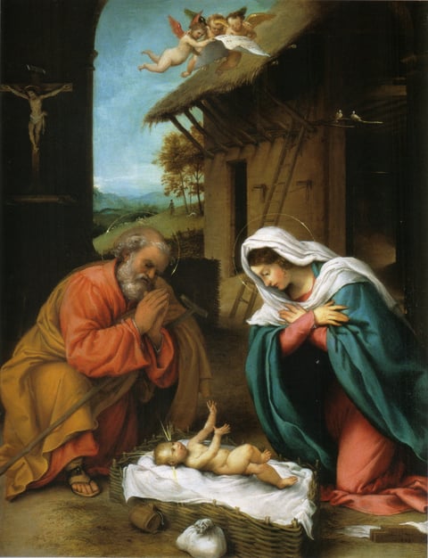 Lorenzo Lotto’s The Nativity: Joseph and Mary kneel over the baby in a basket outside a thatched barn, with a crucifix on the shadowed wall behind Joseph.